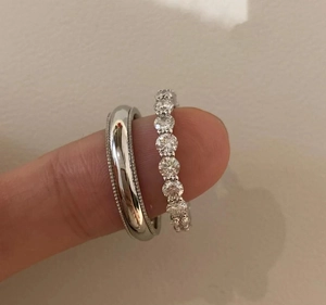 Close-up of S925 sterling silver eternity band and plain ring worn on a finger