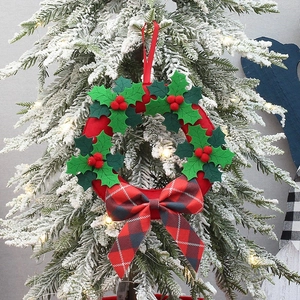 Close-up of a festive Christmas wreath with red berries and a red plaid bow on a snowy tree