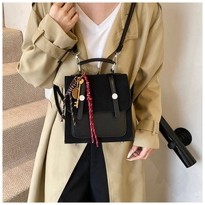 Detalle de un bolso bandolera de cuero negro minimalista con un colgante de llave vintage