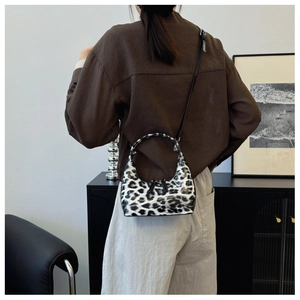 Detail shot of leopard print handbag showing glossy finish and crescent shape in style