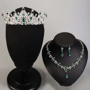 Detail of silver bridal jewelry set with green and clear gemstones on a black bust