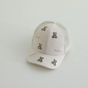 Detailed close-up of brown bear embroidery and breathable mesh on a beige kids' sun hat