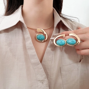 Detail view of model wearing golden resin choker and bracelet with green oval gemstones