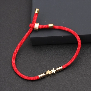 Detail of red adjustable Milan cord bracelet featuring double gold stars on dark background