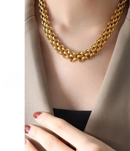 Detail of chunky gold-plated stainless steel chain necklace worn with a beige blazer