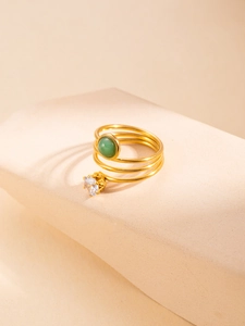 Macro view of triple-layer spiral gold ring with green cabochon and white zircon gem