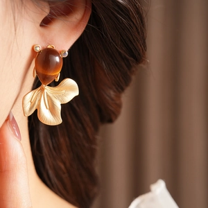 Detail view of vintage fish drop earring with brown translucent resin and gold metal