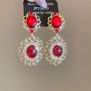 Detailed macro of vintage red gemstone earrings with intricate golden hollow lace trim