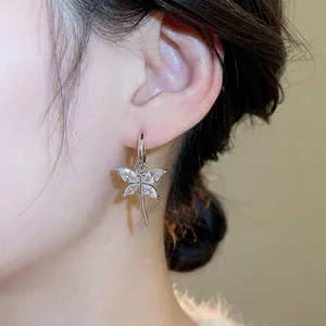 Elegant silver dragonfly earrings with sparkling zircon wings on female model's ear