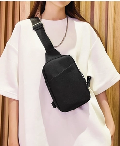 Close-up of a minimalist black crossbody bag showing fabric texture and strap detail