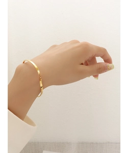 Detail shot of a minimalist gold twisted bangle featuring elegant thin metal wire design