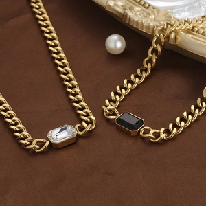 Detail van gouden Cubaanse schakelkettingen met heldere en zwarte kristallen hangers