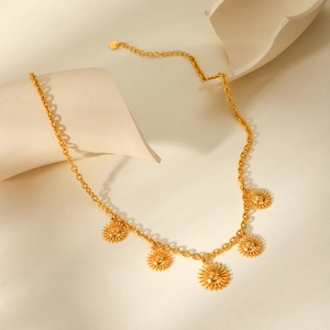 Gold stainless steel sun face pendant necklace displayed on a minimalist artistic background