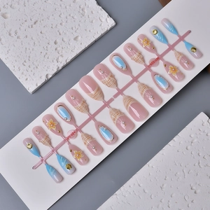 Macro detail of almond press-on nails with blue ocean waves, shells and 3D floral accents