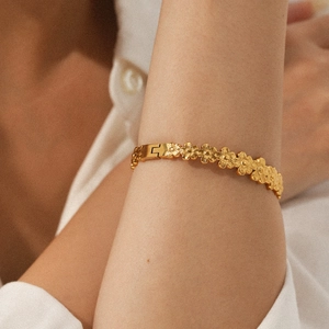 Detailed view of 18K gold plated flower cuff bangle on woman's wrist with petal texture