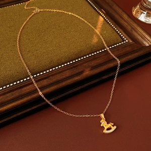 Close-up of gold-plated horse pendant necklace with inlaid crystals on a vintage background