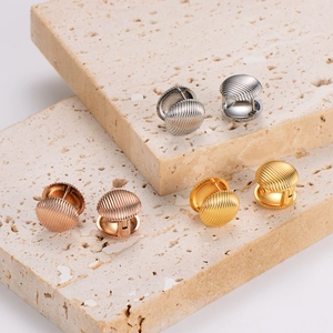 Three-tone ribbed dome stainless steel clip earrings on a natural travertine stone stand