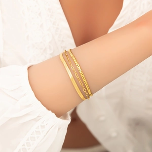 Detailed view of three layered gold stainless steel chains worn by a female model