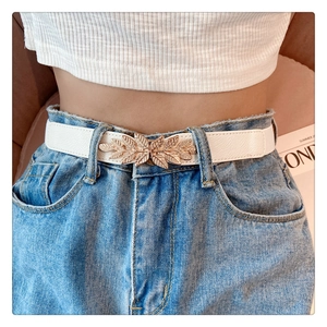 Close-up of white elastic waist belt featuring a gold leaf-shaped metal buckle on jeans
