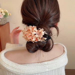 Detailed back view of a soft peach floral hair clip styled on a woman's dark hair
