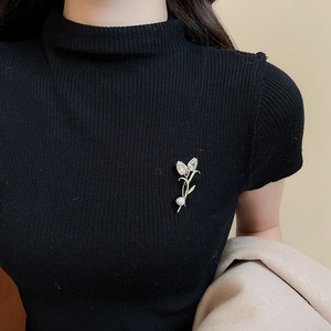 Detail of 14K gold plated tulip brooch with cubic zirconia and pearl on black sweater