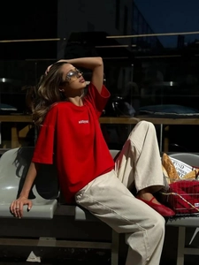 Dettaglio dell'istampa bianca ASSISTIVE su una t-shirt in cotone rosso in stile urban street