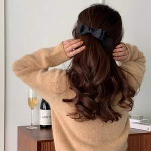 Elegant large black satin bow hair clip worn by a model with long brown wavy hair