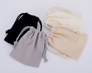 Set of four cotton drawstring pouches in black, grey, and cream with natural texture