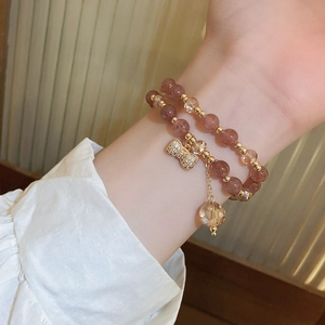 Detail of double-layered pink strawberry quartz bracelet with a sparkling crystal bow charm