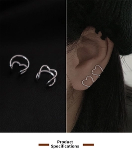 Close-up of minimalist silver heart-shaped ear cuffs on model and dark background