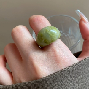 Detail of green resin ring with marble texture worn on finger for a vintage minimal look