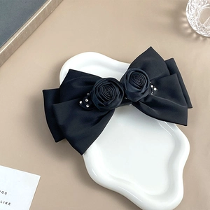 Detail of black satin bow hair clip with handmade roses and sparkling rhinestones
