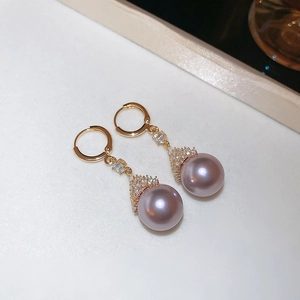 Detail of gold earrings with purple pearl pendants and sparkling zircon accents