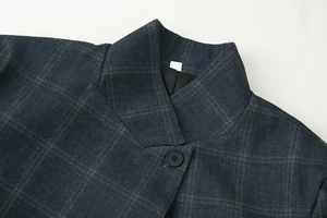 Détail du revers et du bouton d'un blazer à carreaux gris foncé avec texture de tissu