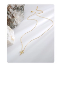 Macro shot of gold cross necklace featuring four sparkling cubic zirconia on a stone background