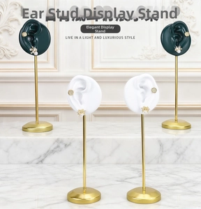 Detailed view of dark green resin ear mold display stand with gold metal rod and base
