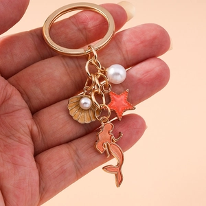 Golden keychain with mermaid shell and starfish charms in coral and beige enamel finish