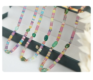 Détail de colliers faits main avec pierres naturelles colorées et perles dorées sur boîte