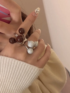 Detail of silver-finish layered open rings with brown and marble white spheres