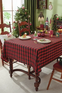 Detail of red and green plaid Christmas tablecloth with gold silk fringe on a wooden table