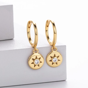 Detailed view of gold hoop earrings featuring a hollow star pendant with clear zircon