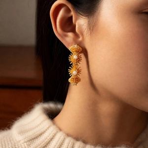 Gros plan de boucles d'oreilles fleurs en cascade plaquées or 18 carats avec perles