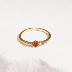 Close-up of adjustable gold-plated ring featuring a round orange zircon and side diamonds