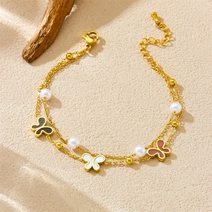 Bracciale a doppio strato dorato con farfalle e perle su sfondo materico