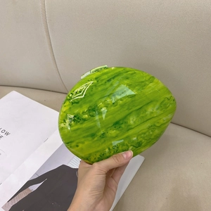 Detail shot of a green marble pattern oval evening clutch with a glossy polished finish