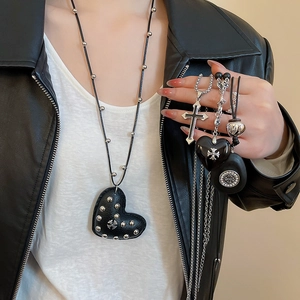 Detail view of gothic heart pendants and cross charms on black leather cords