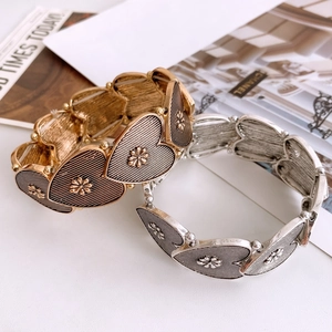 Detail of vintage heart-link bracelets in gold and silver with textured floral patterns