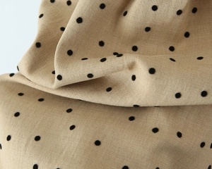Detailed macro view of khaki fabric with black polka dots and fine woven texture