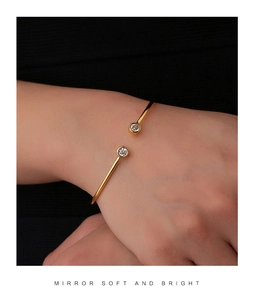 Macro detail of gold-plated open bangle featuring dual brilliant round-cut zircon stones