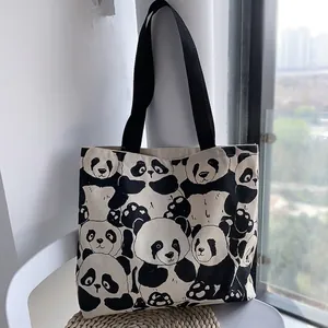 Close-up of canvas tote bag featuring dense black and white panda print with black straps